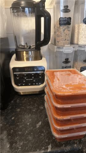 Soup portioned into containers ready to freeze next to the Ninja Foodi Blender and Soup Maker